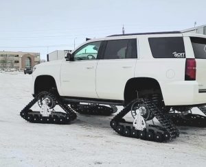 A custom built white Chevrolet Tahoe with tracks instead of wheels and tires.