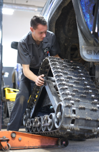 An automotive technician putting tracks on a blue truck.